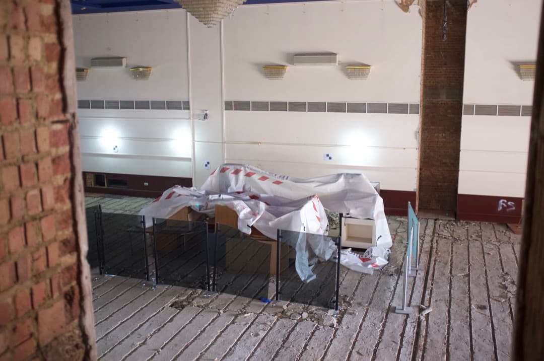 Photo looking into a large gallery, with no floor and piles of rubbish