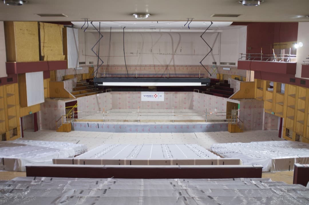 Photo from the back of a concert hall, chairs covered in plastic
