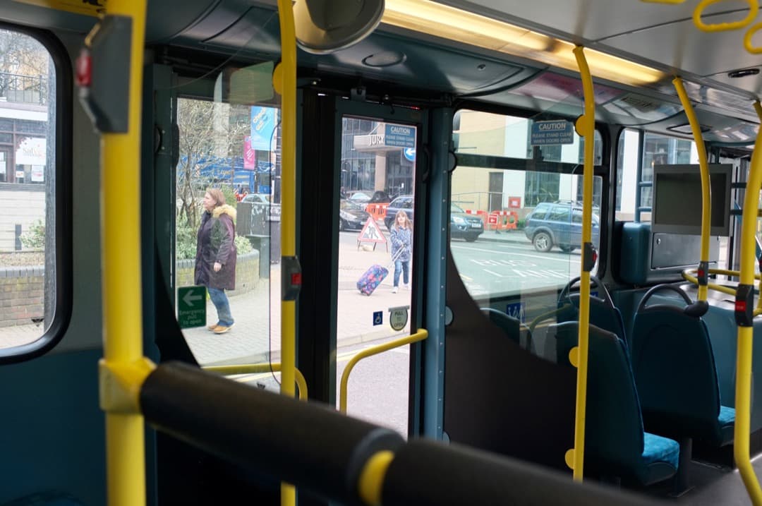 Photo of a girl with a bag running after a women on the street, taken from a bus